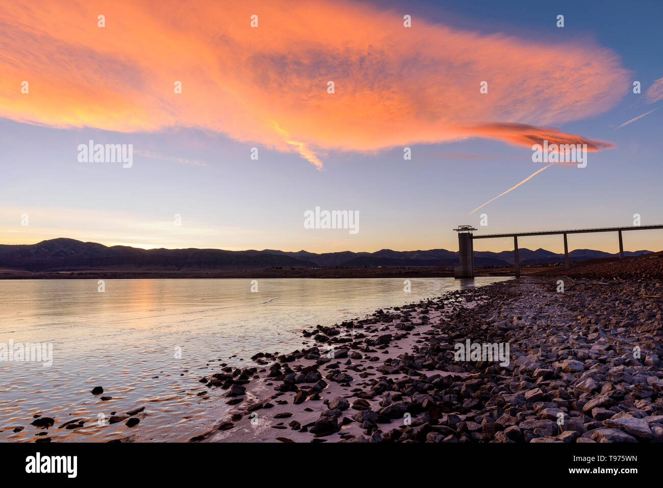 Sunset Reservoir - Colorful winter sunset clouds rolling over frozen Chatfield Reservoir at foothill of front range of Rocky Mountains. CO, USA. Stock Photo