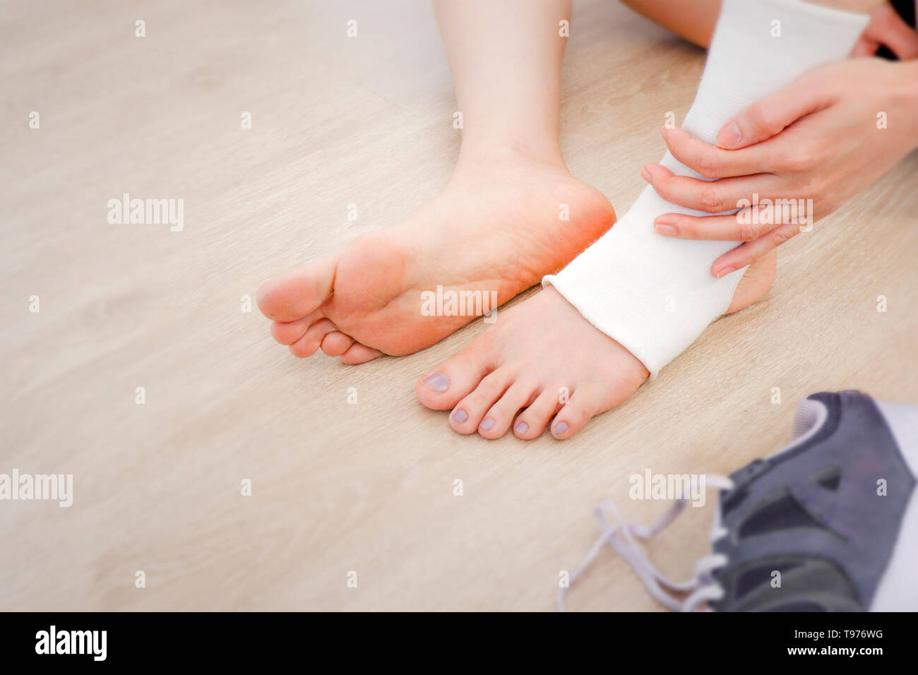 Woman Foot with Gauze Elastic Bandage and Purple Shoes (Sneakers). Hands on Sports Injury