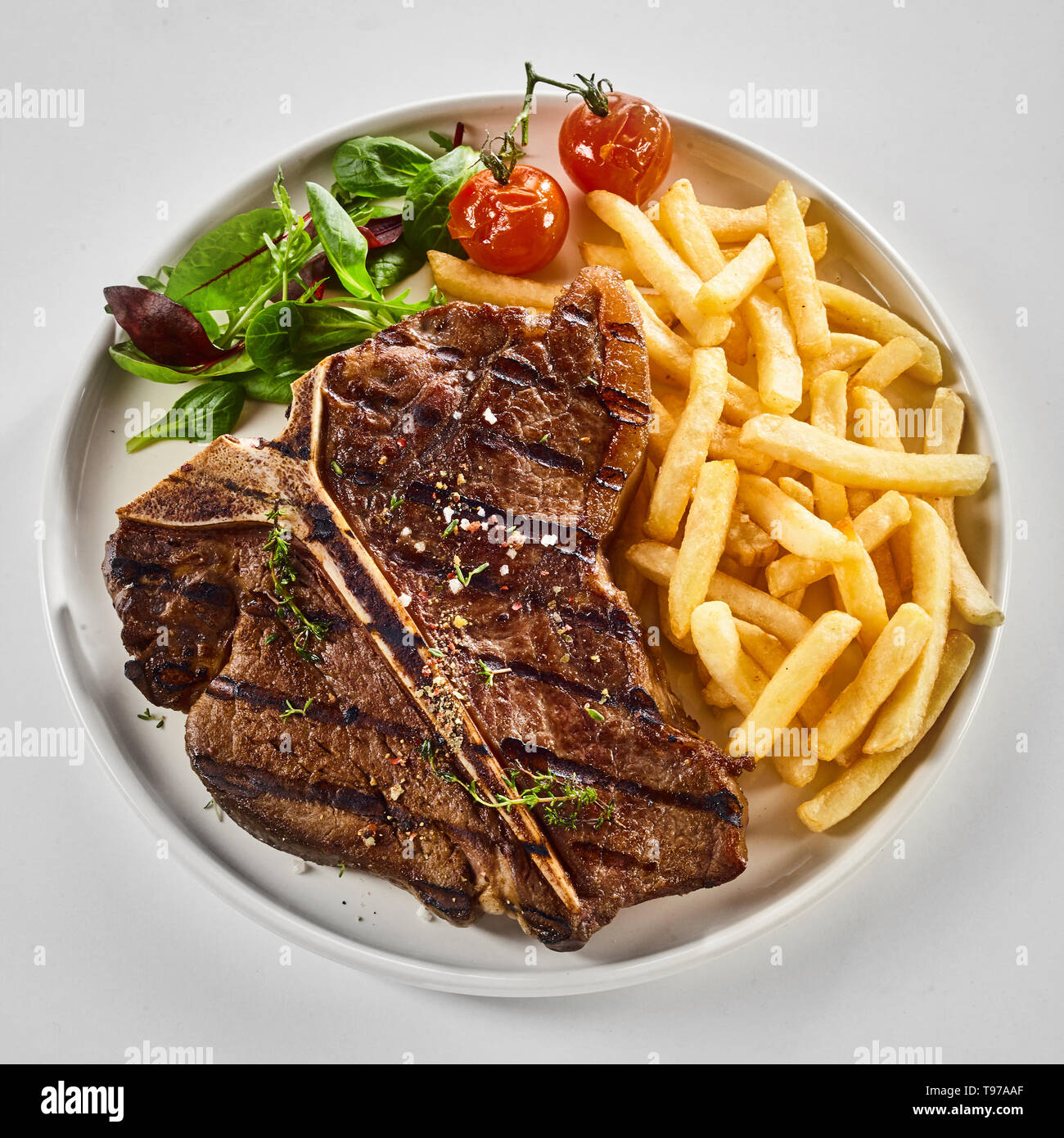 Tasty grilled or barbecued Tbone steak with fried potato chips, salad