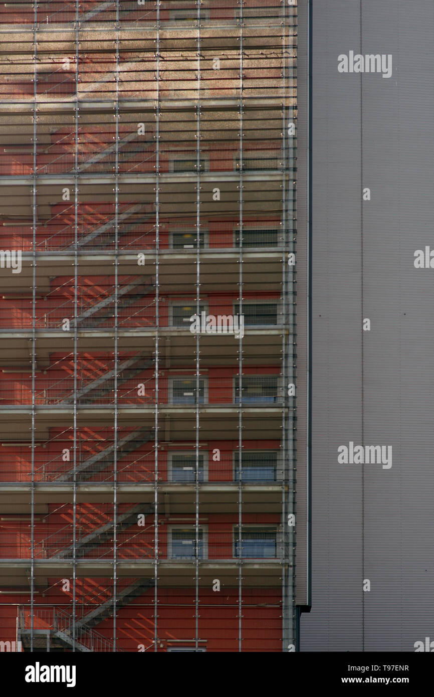 The exterior staircase of a residential and commercial building casts shadows behind bars. Stock Photo