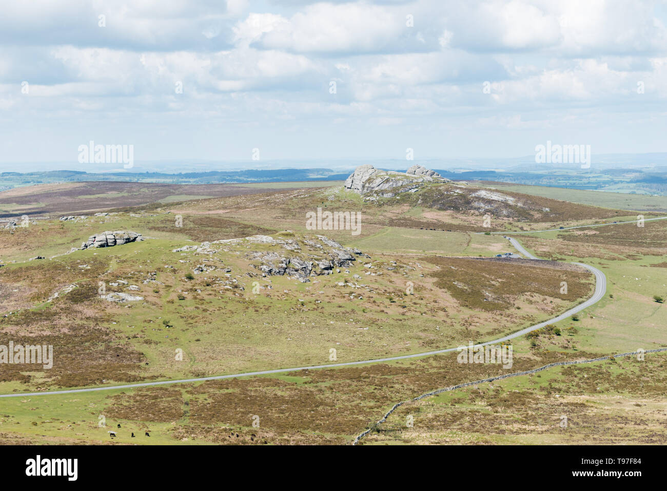 From left to right a view of Emsworthy Rocks, Saddle Tor and Haytor across moorland of Dartmoor National Park, Devon, UK, with a winding road. Stock Photo