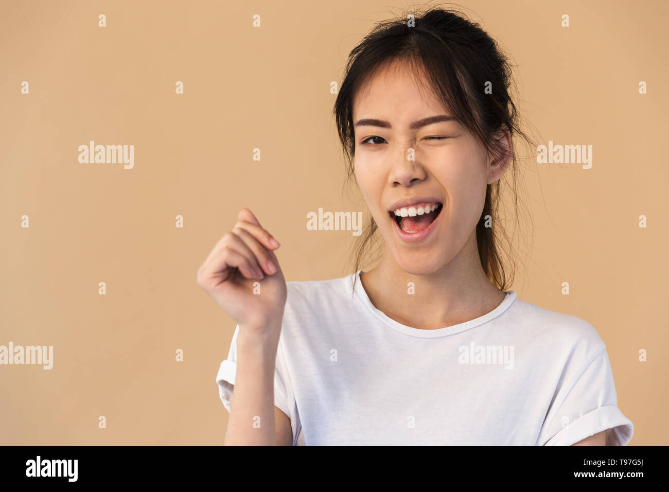 Photo of affable korean woman wearing basic tshirt smiling and winking