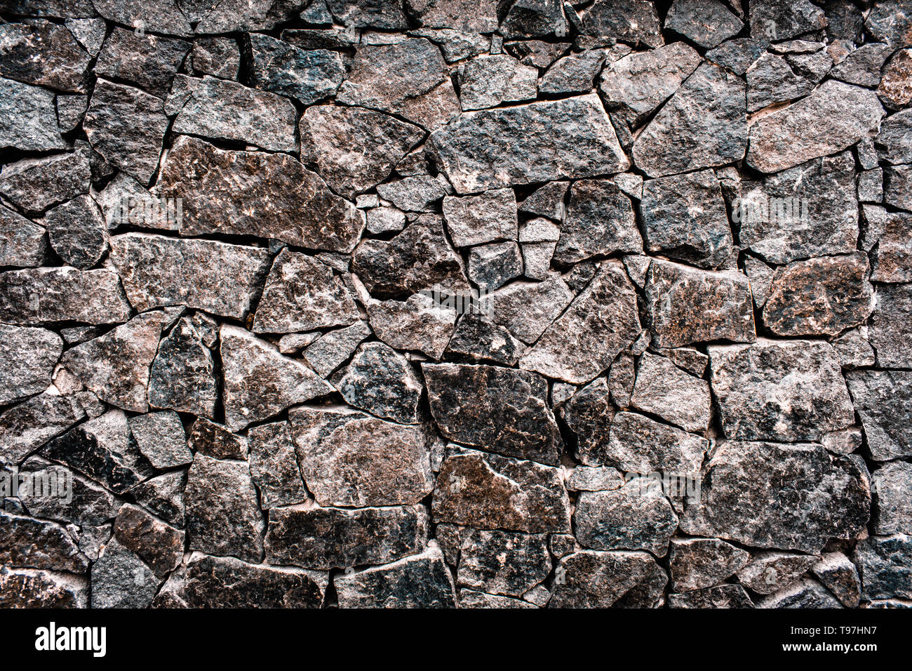 textured texture of a dark and gray old stone wall. Wallpaper for