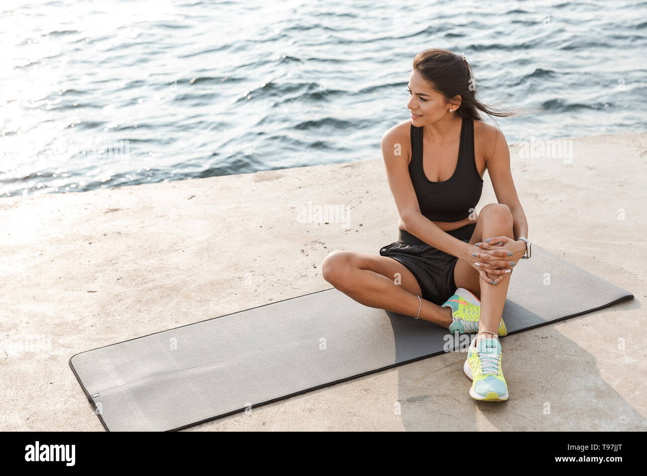 Attractive young fitness woman wearing sportswear sitting on a fitness ...