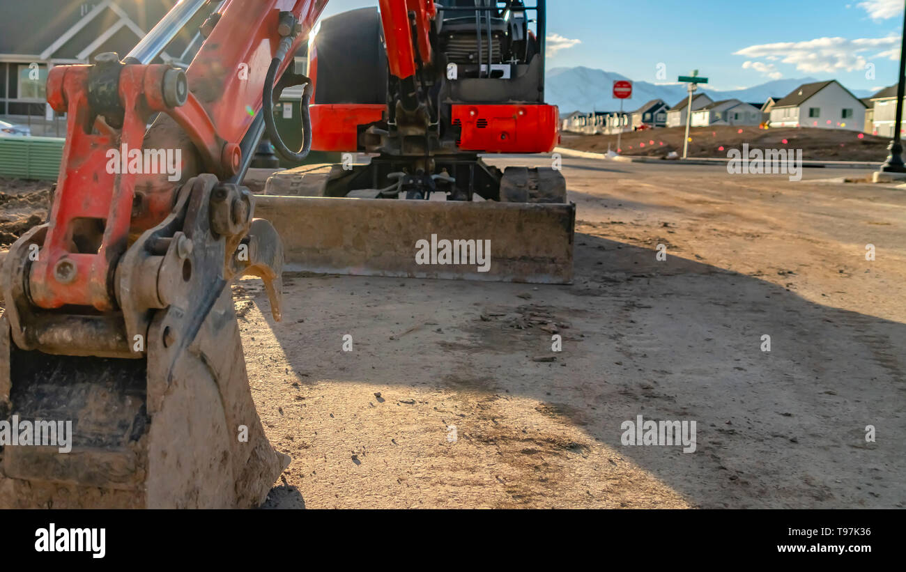 Panorama Close up of a red excavator with an attched grader blade viewed on a sunny day Stock Photo