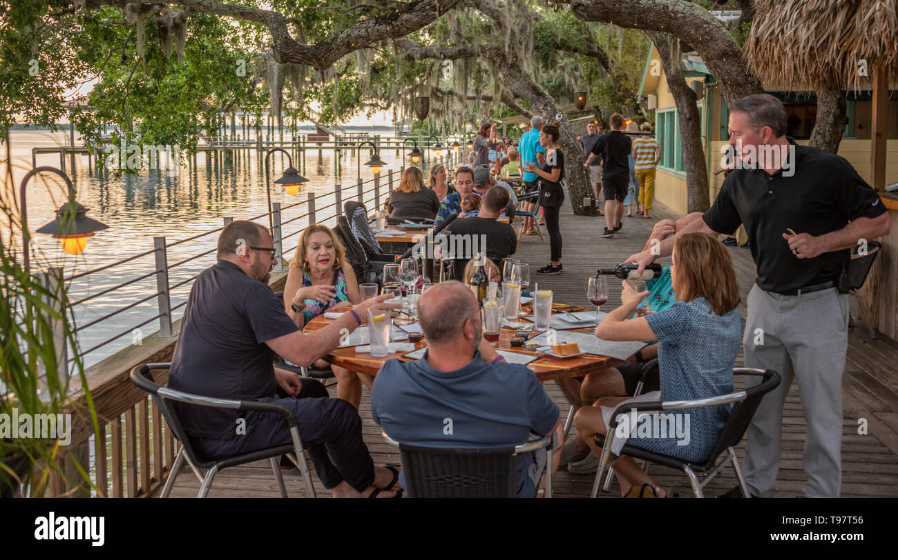 Sunset dining under Florida live oaks on the waterfront deck at Caps on the Water, a local seafood restaurant on the Intracoastal in St. Augustine, FL. Stock Photo