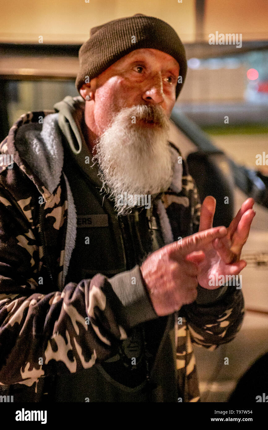 A bearded volunteer helps released prisoners with food and support from a van parked outside a county jail at night in Santa Ana, CA. Stock Photo