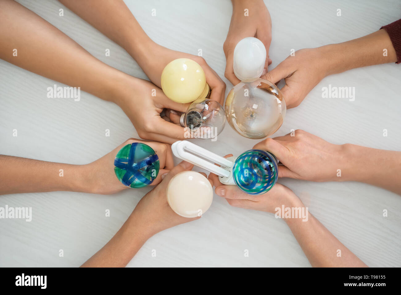 Female hands with different light bulbs on light background Stock Photo