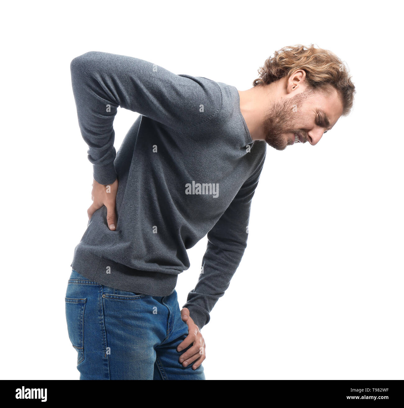 Young man suffering from back pain on white background Stock Photo - Alamy