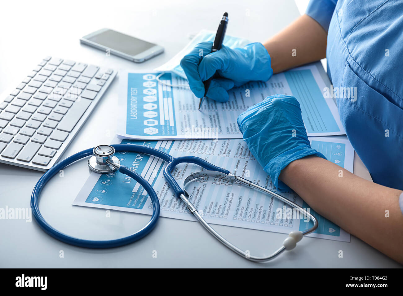 Female doctor filling in laboratory test request form on white table