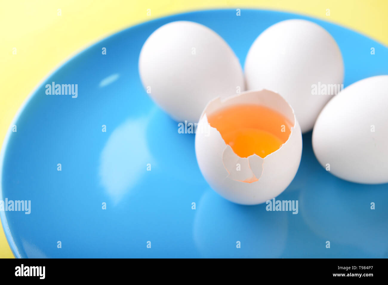 Plate with cracked and whole chicken eggs on color background, closeup ...