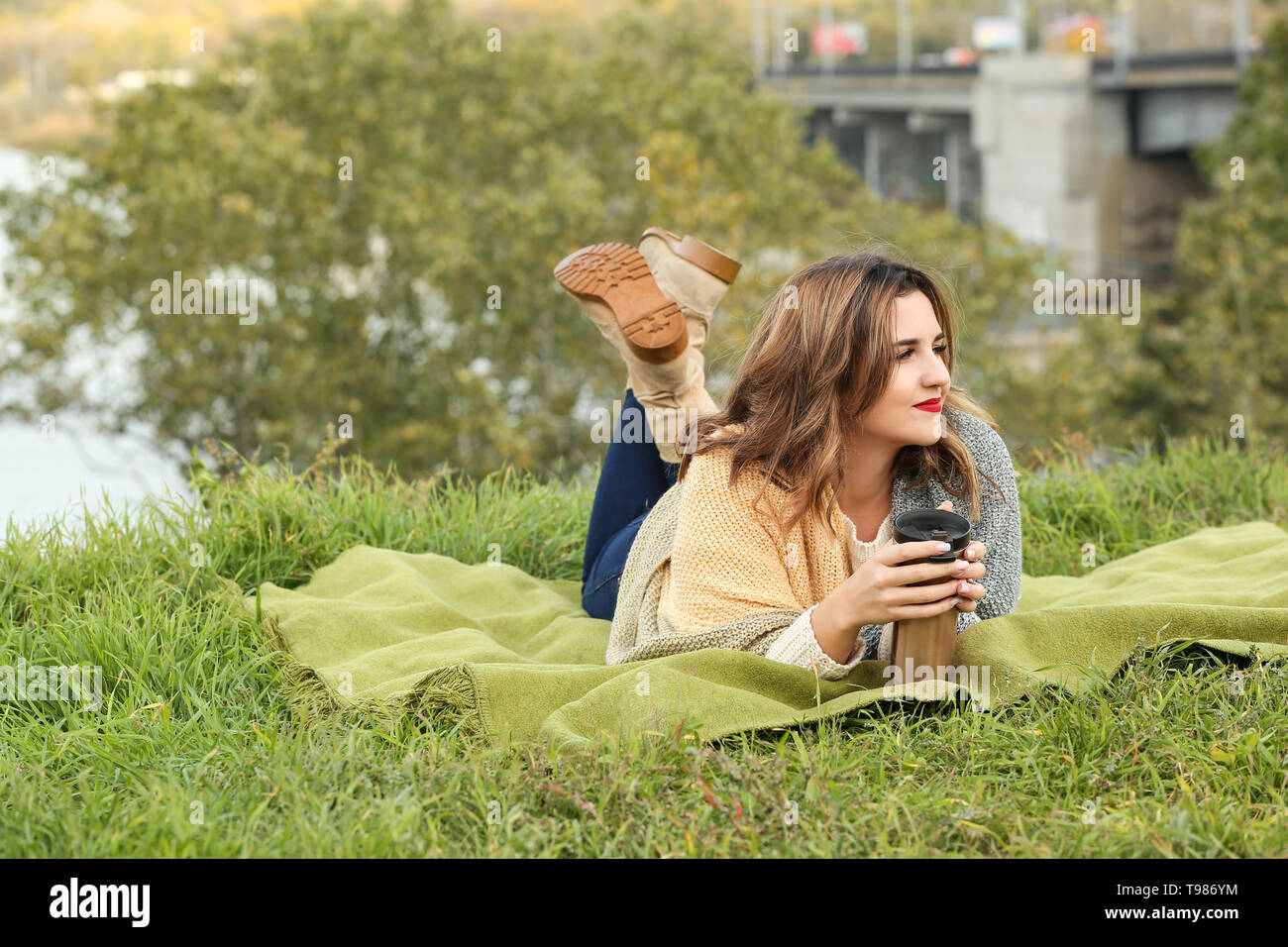 https://c8.alamy.com/comp/T986YM/beautiful-young-woman-with-thermos-resting-on-plaid-outdoors-T986YM.jpg