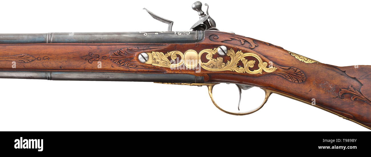 A German flintlock rifle/shotgun combination, circa 1730 Newly blued, over-and-under round barrels with an eight-groove rifled bore and a smooth bore in 13 mm calibre with silver front sight on the upper side. The rifle barrel decorated with ornamental silver inlays and standing male figure. Florally engraved flintlock with movable powder pan chiselled on the side in the shape of a monster. Monogram 'IVB' between the arms of the frizzen spring. Carved walnut full stock with horn nose and finely chiselled brass furniture. The openwork side plate w, Additional-Rights-Clearance-Info-Not-Available Stock Photo