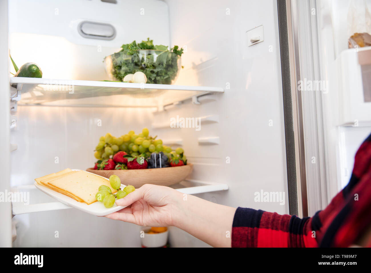 Woman takes cheese from fridge full of food Stock Photo Alamy