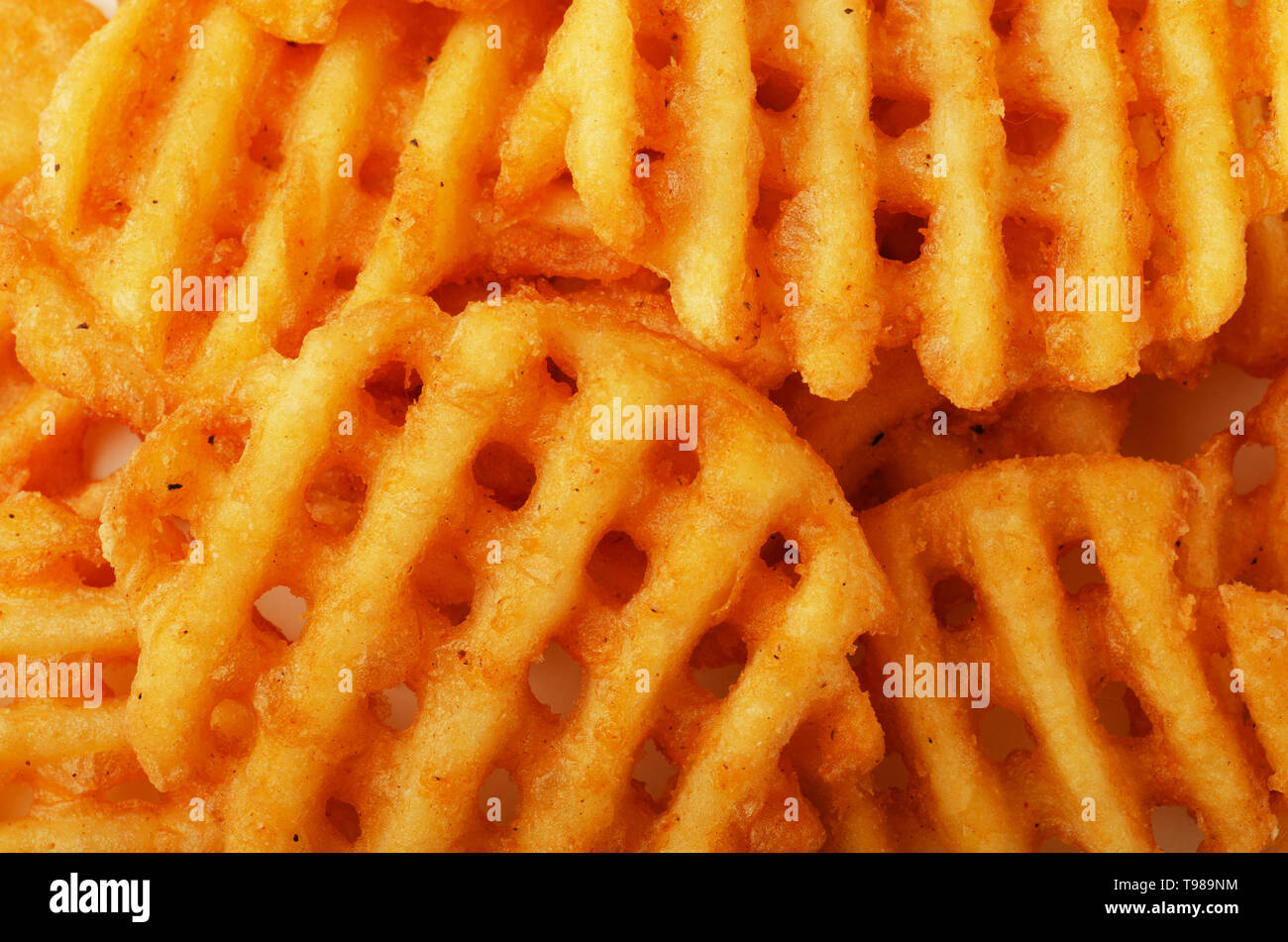 Crispy potato waffles fries, wavy, crinkle cut, criss cross cries as background Stock Photo