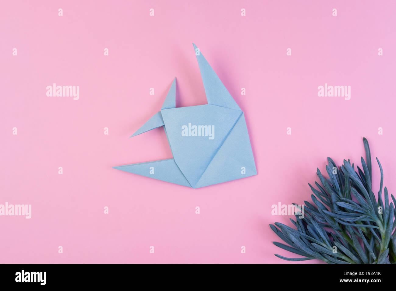 Origami light blue fish on pink minimalistic background. Paper sea