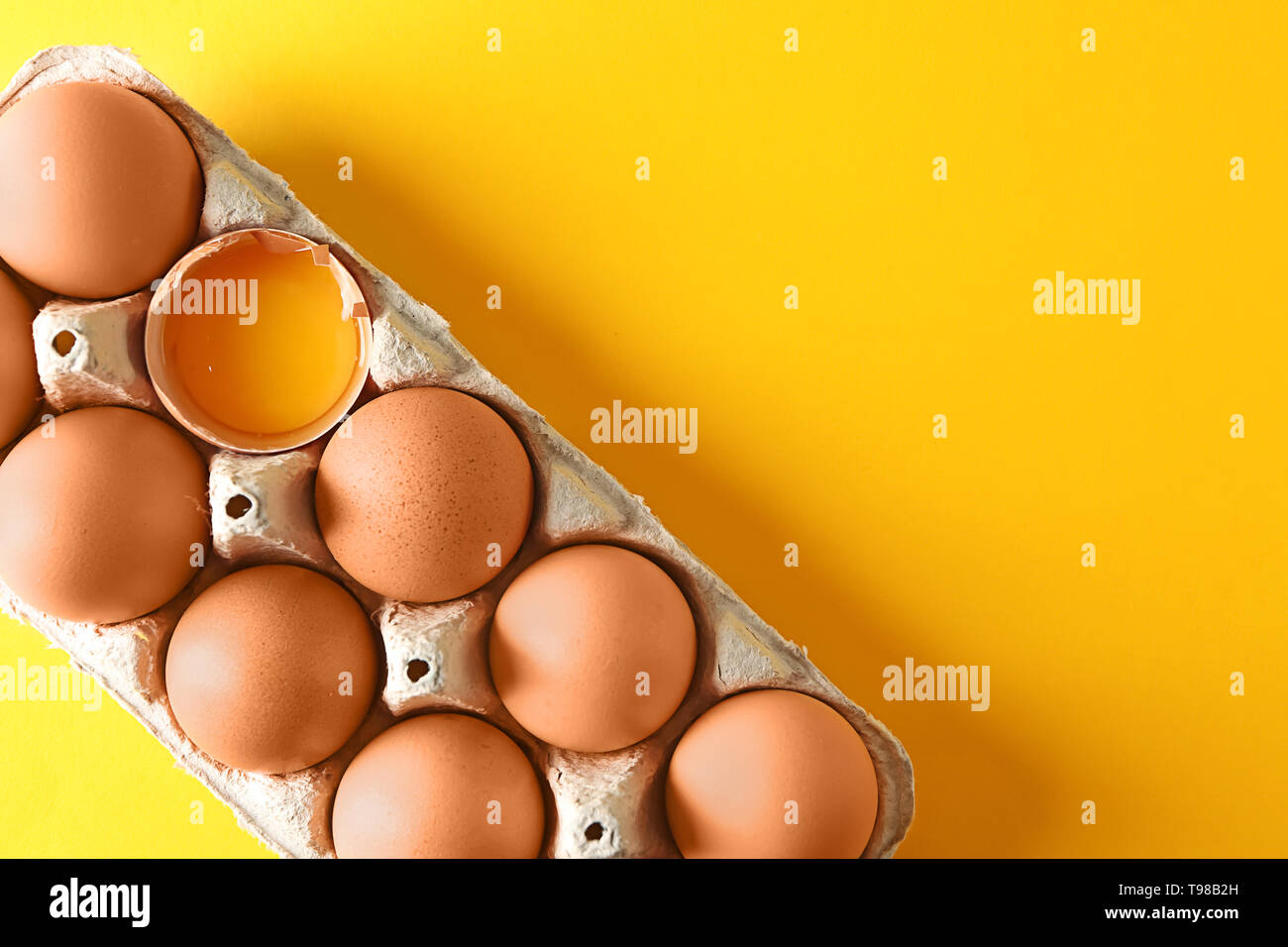 Cracked and whole chicken eggs in carton box on color table Stock Photo ...