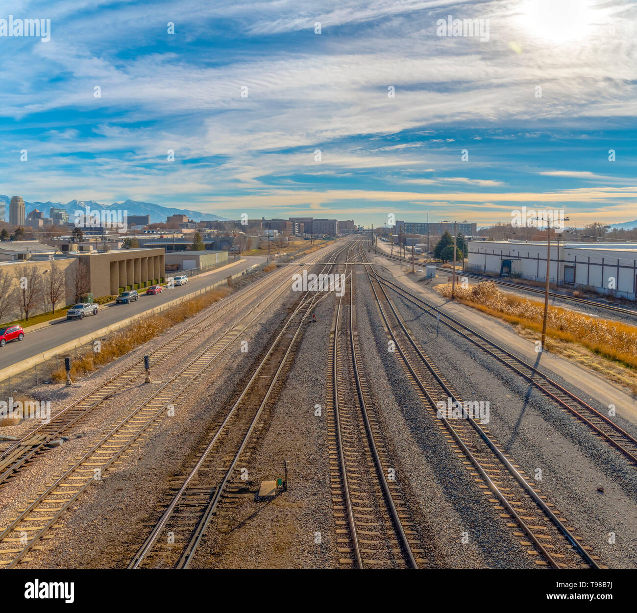 Railroad tracks and roads with mountain and vibrant cloudy blue sky background Stock Photo