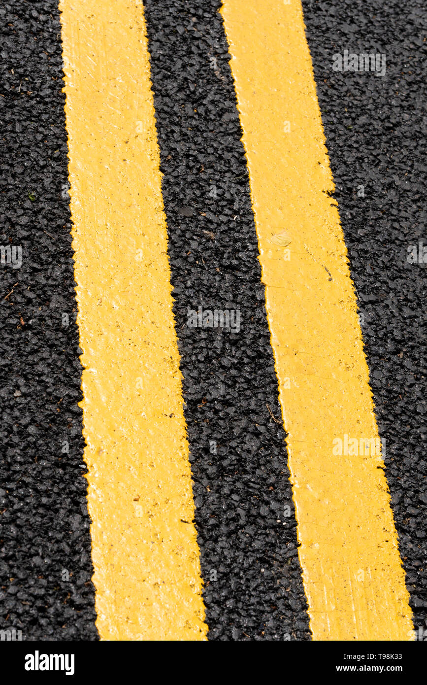 Freshly painted double yellow lines on new black tarmac road surface