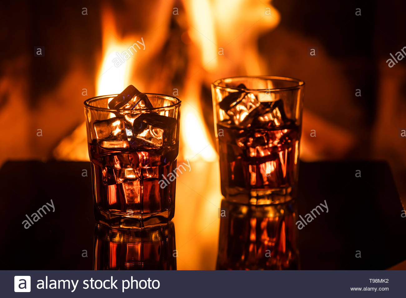 Glass Of Whiskey With Ice Near The Fireplace Stock Photo