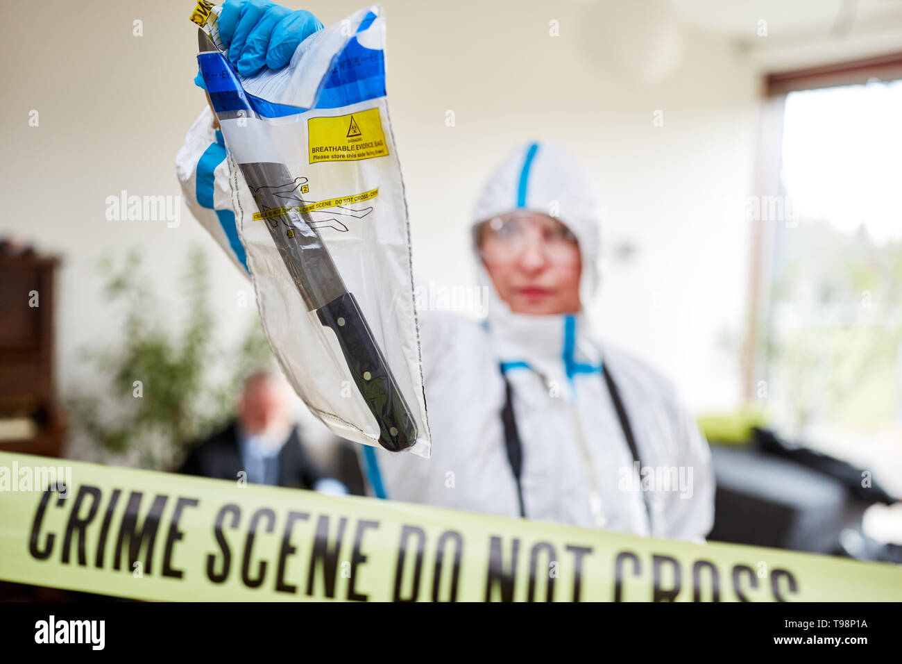 Police forensic officers ensure knives at a crime scene Stock Photo