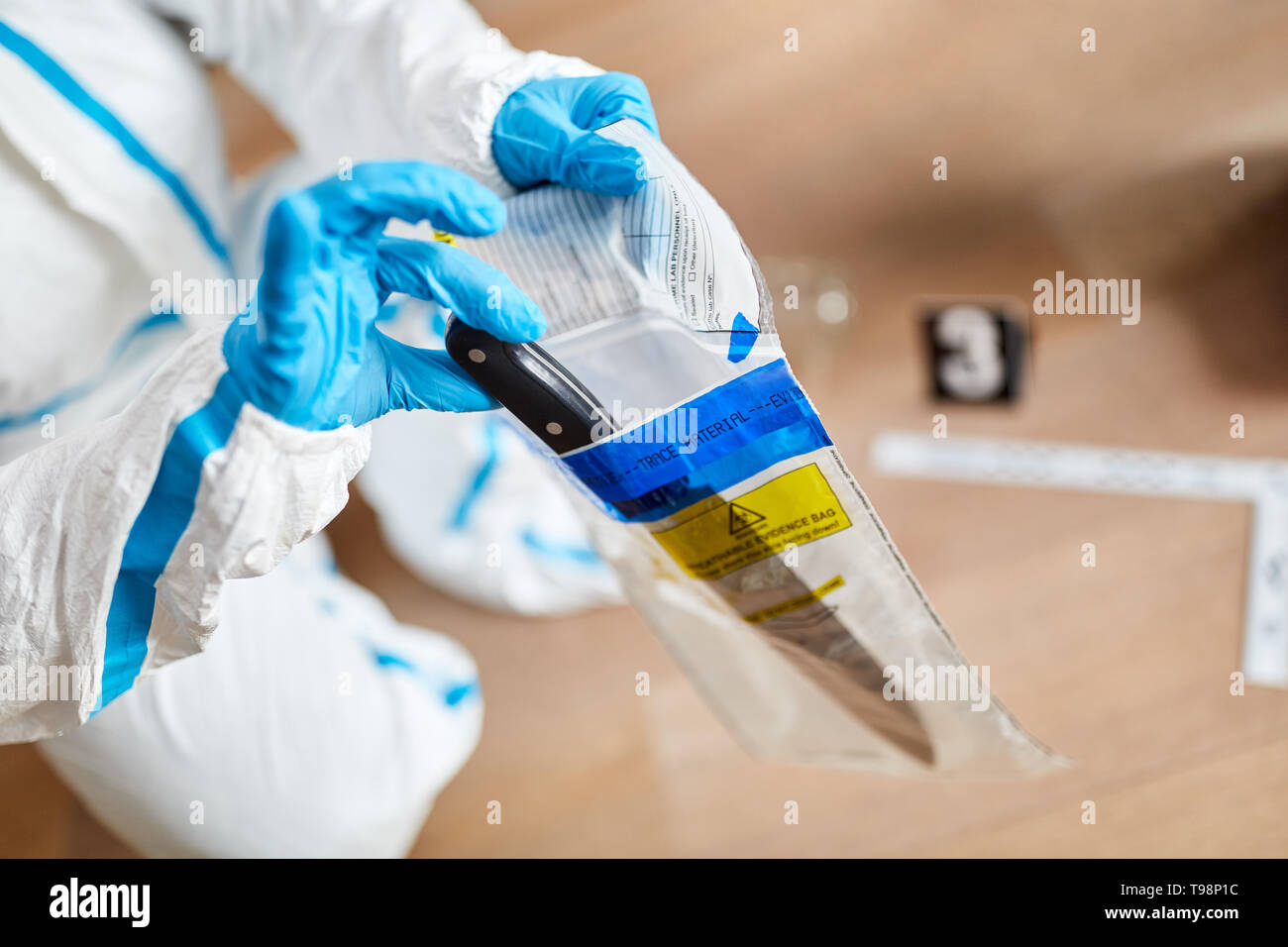 Forensic police at the scene of a crime packs knives in a bag of evidence Stock Photo