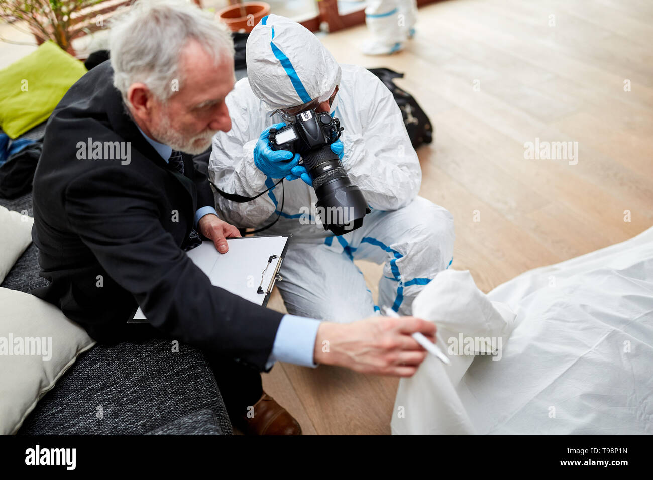 Police photographer photographs body after murder at crime scene Stock Photo