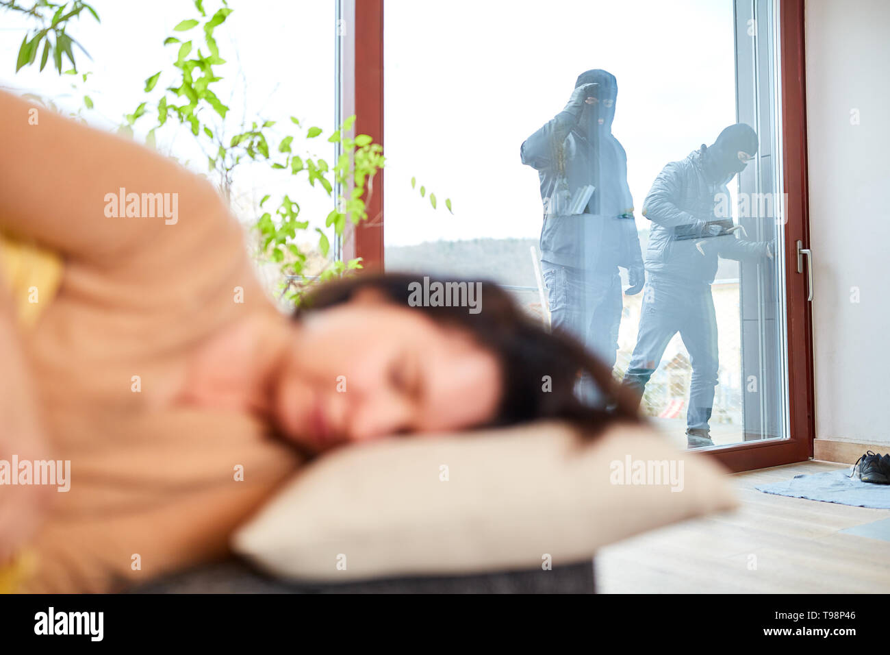 Burglar in robbery with a sleeping woman in the house Stock Photo