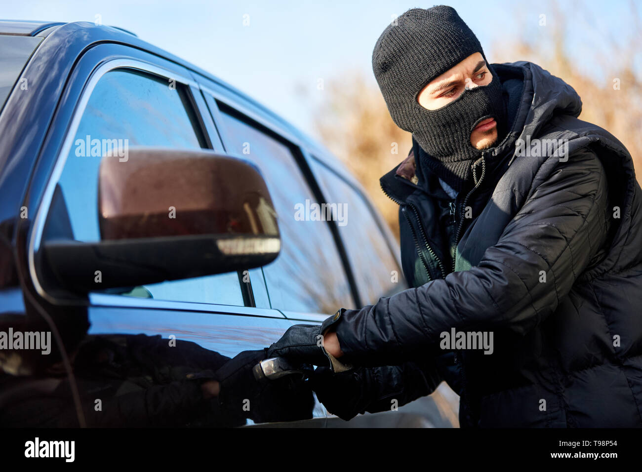 Car thief in car theft is at the car door Stock Photo