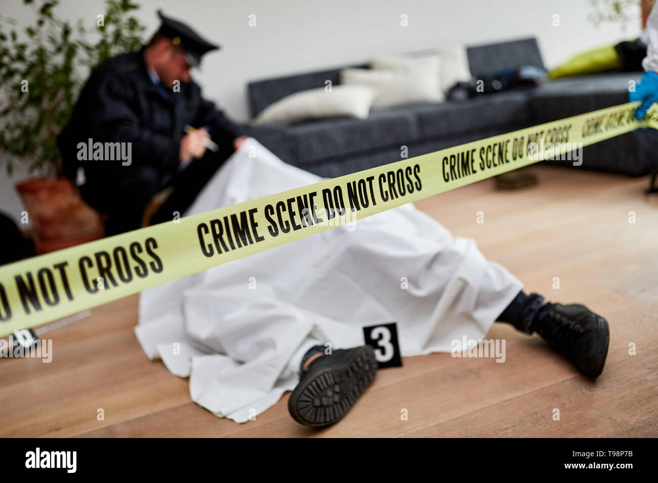 Policeman next to dead body investigating murder at crime scene Stock Photo