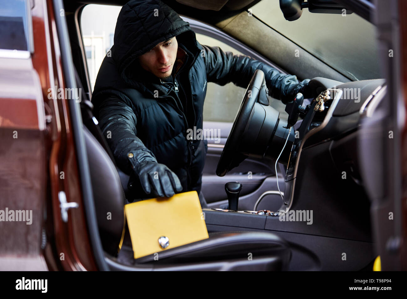 Thief stealing a handbag from an open car Stock Photo