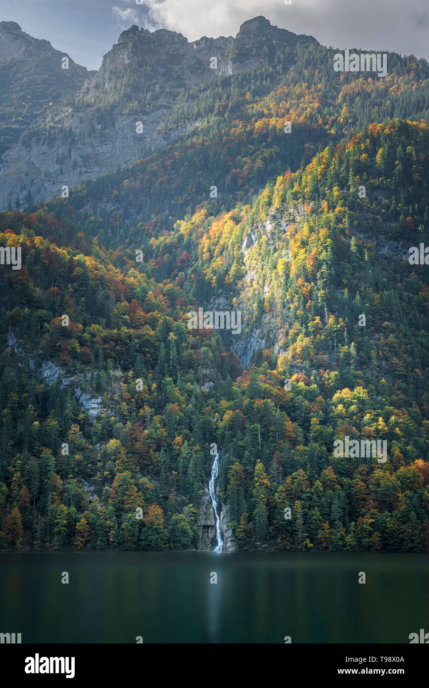 Illuminated autumn forest with waterfall at lake Königssee, Berchtesgadener Land, Bavaria, Germany Stock Photo