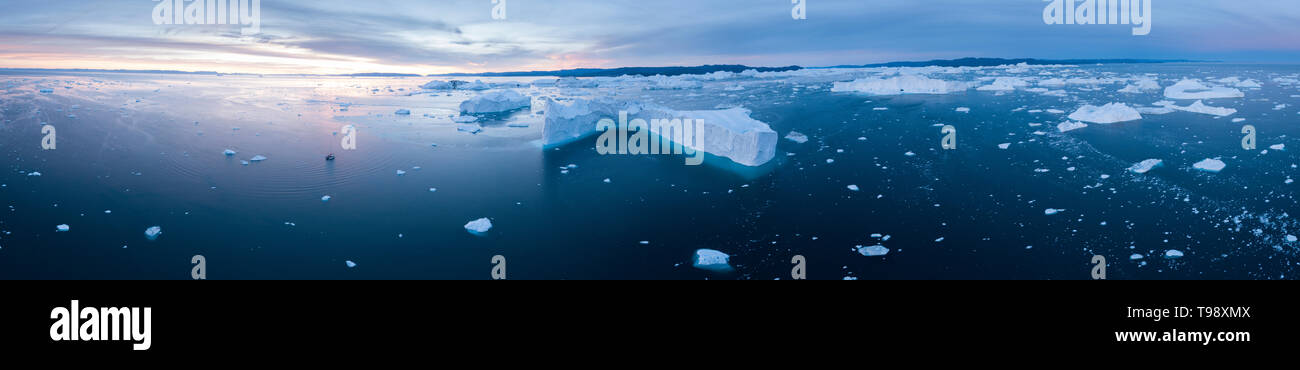 Icebergs and sailboat in Disko Bay on Midsummer, Greenland Stock Photo