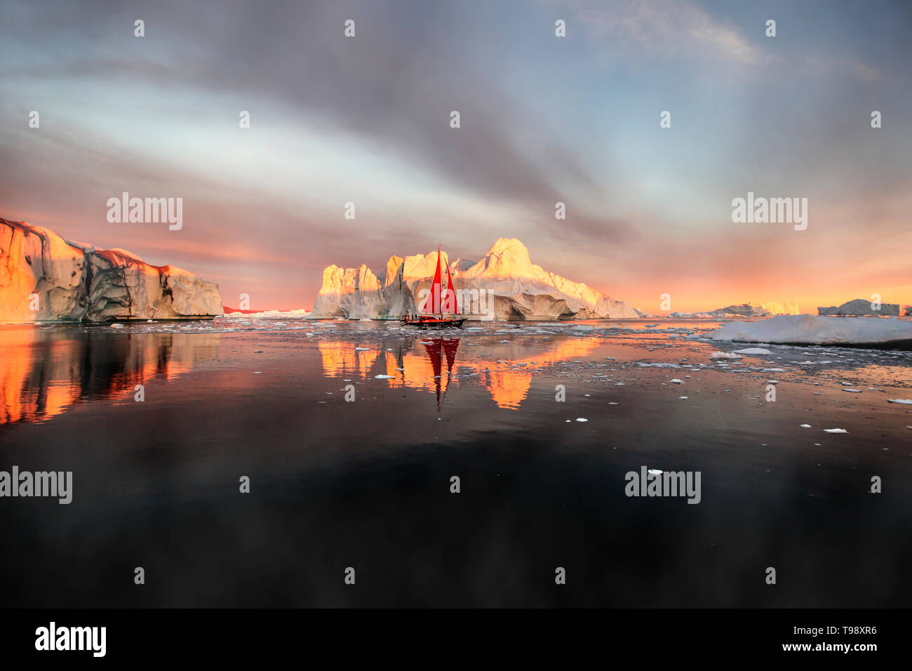 Icebergs and sailboat in Disko Bay on Midsummer, Greenland Stock Photo