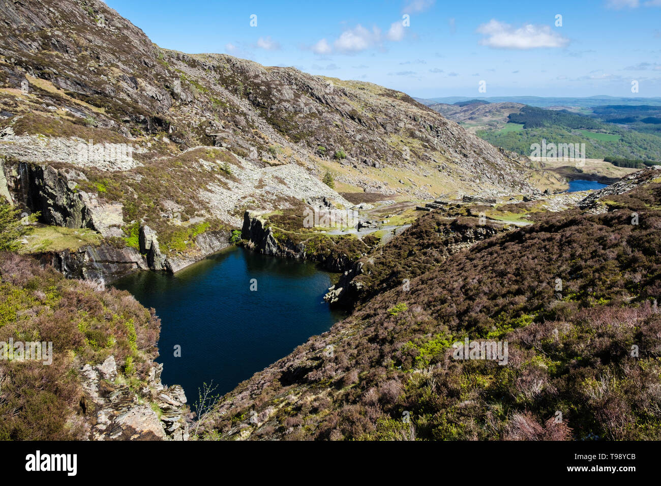 Flooded disused slate quarry pit and slag heaps on path route to Carnedd Moel Siabod mountain in Snowdonia National Park. Capel Curig Conwy Wales UK Stock Photo