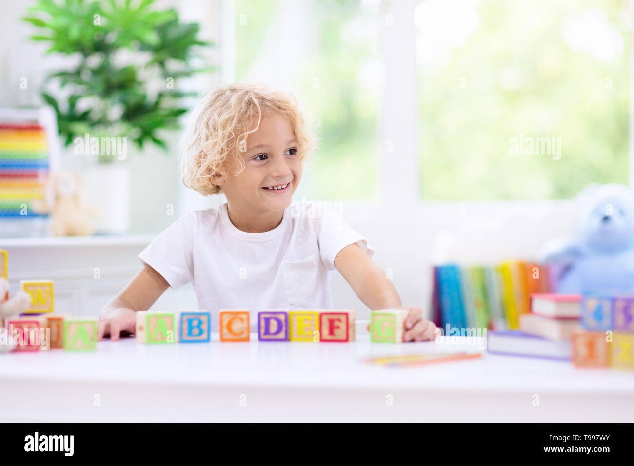 Child learning letters and numbers. Kid with colorful wooden abc blocks