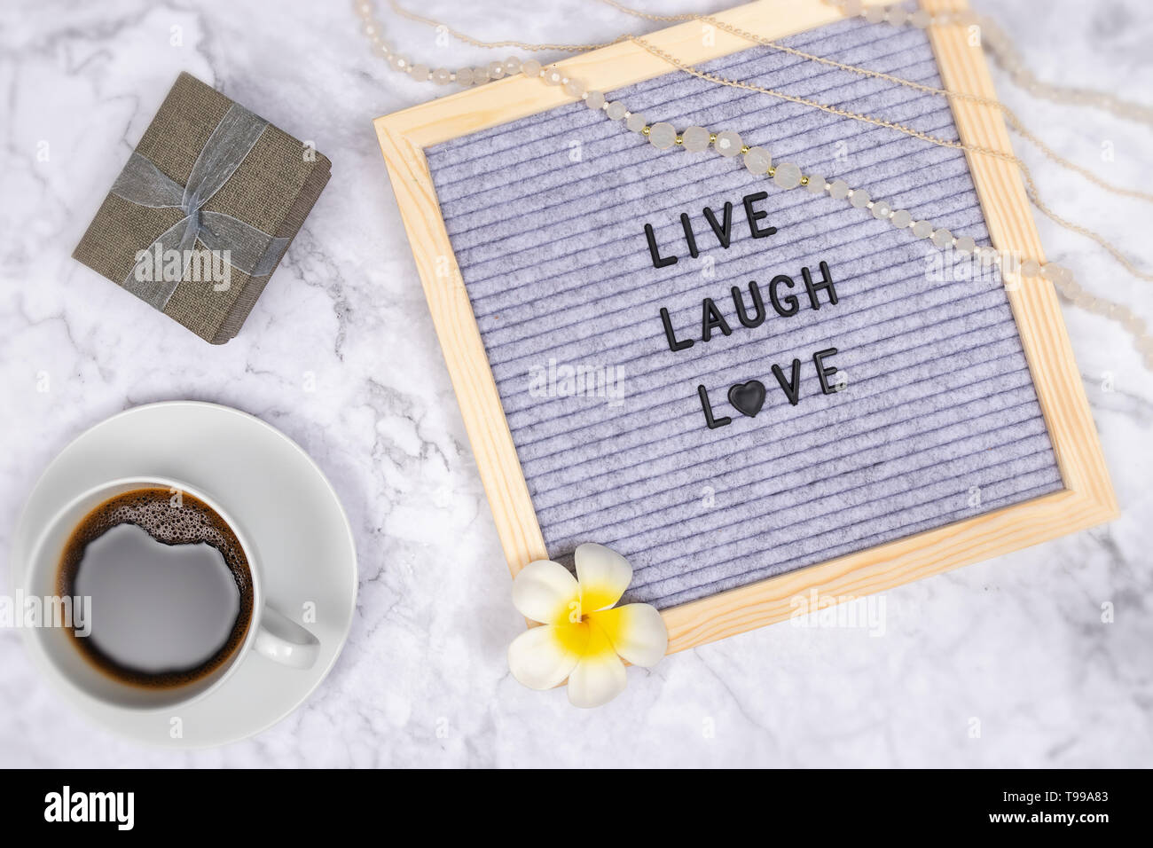 word live laugh love on letter board on white marble desk background with coffee cup and gift box , decoration with flower and luxury pink necklace Stock Photo