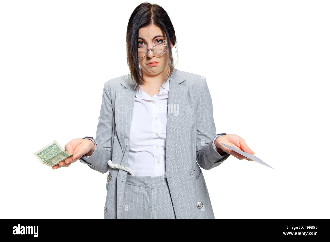 No time for jokes, boss. Young woman in grey suit getting a small salary and not believing her eyes. Shocked and outraged. Concept of office worker's troubles, business, problems and stress. Stock Photo