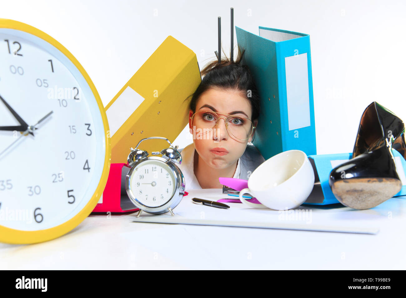 No strength. Young woman getting a lot of work and deadline, being under the pressure of the deals. Pressed by folders with papers. Concept of office worker's troubles, business, problems and stress. Stock Photo