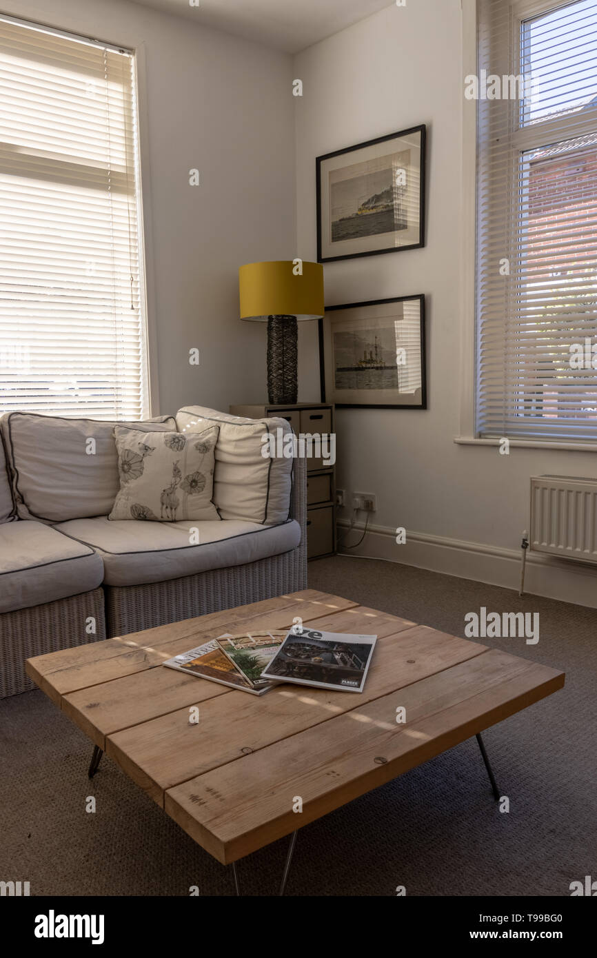 A modern light Living room in and English home with wooden coffee table and interior design magazines in the foreground Stock Photo
