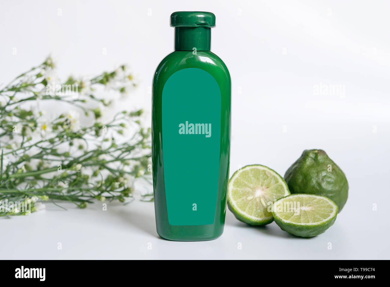 natural products for hair concept. green plastic bottle with blank label contain herbal bergamot shampoo decorate with slide kaffir limes ,kaffir leaf Stock Photo