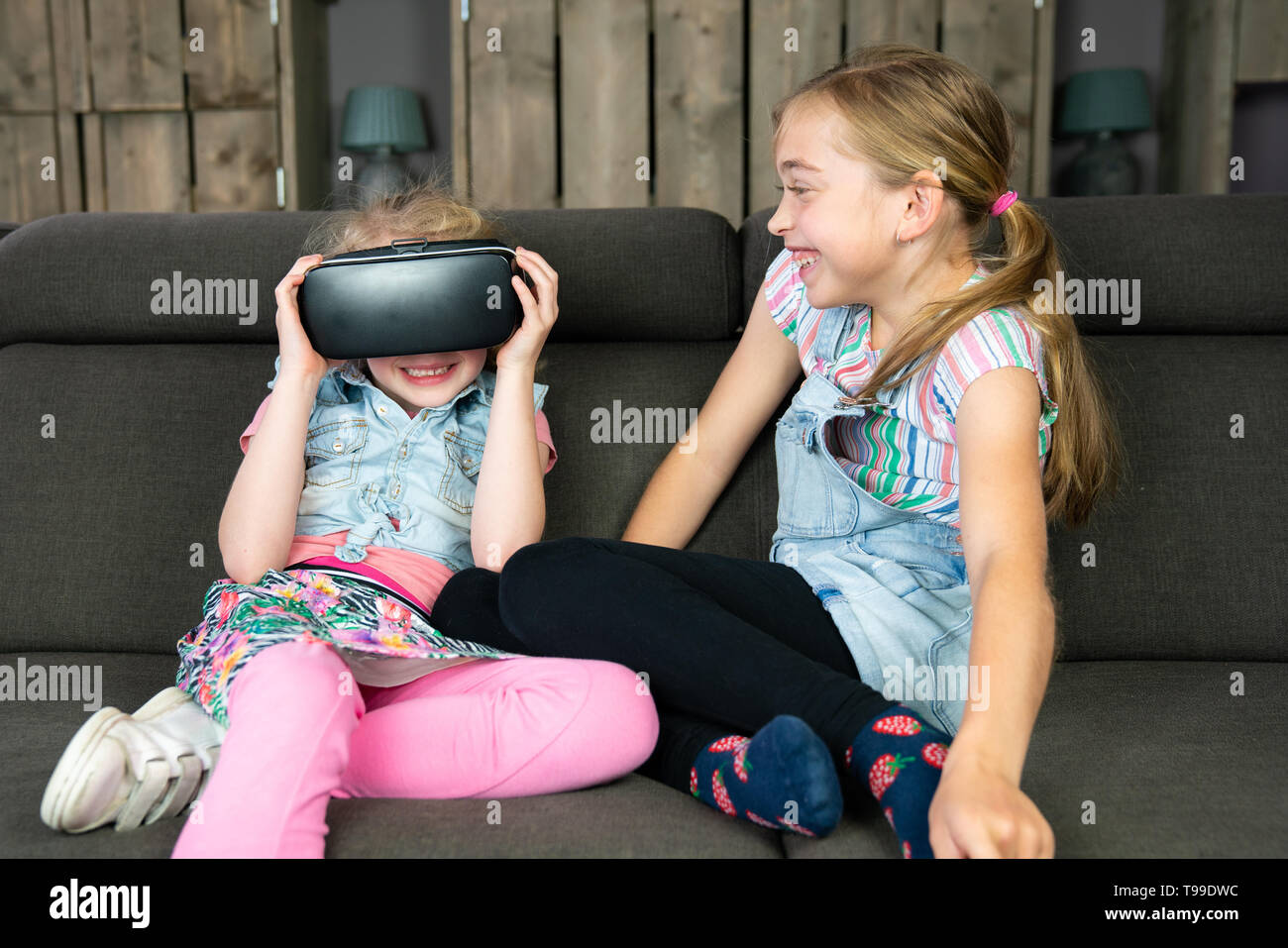 Portrait of two girls, they are having fun with a virtual reality headset at home. Everyday futurism Stock Photo