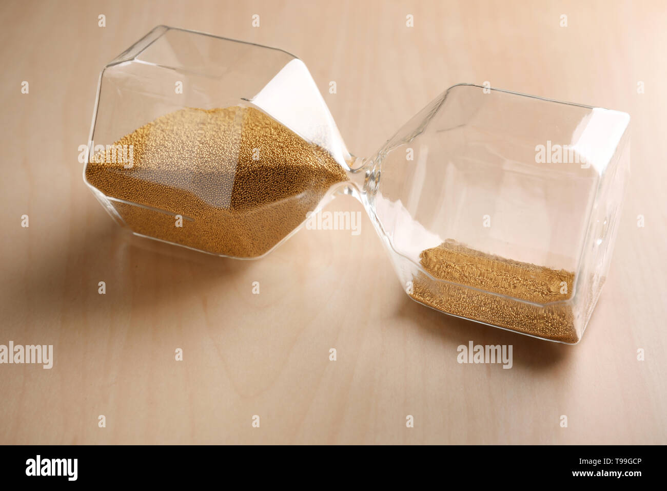 Crystal hourglass with golden sand on wooden table. Deadline concept