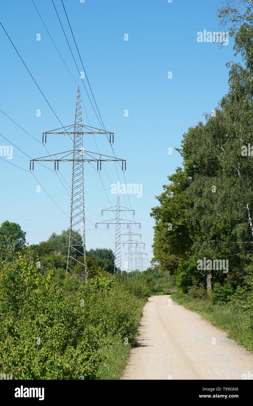 overhead high-voltage power line alongside footpath trough german countryside Stock Photo