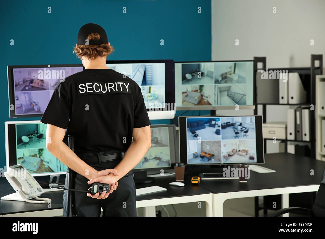 Security guard with portable radio transmitter monitoring modern CCTV