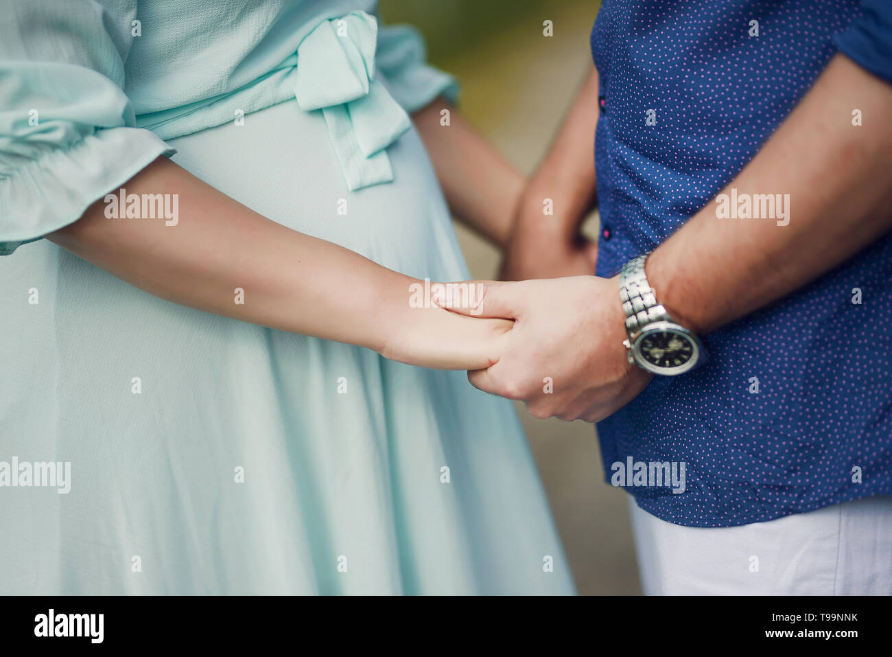 Caucasian couple holding hands with focus on the pregnant woman's beautiful round tummy, concept for happy family expecting a baby, couples pregnancy Stock Photo