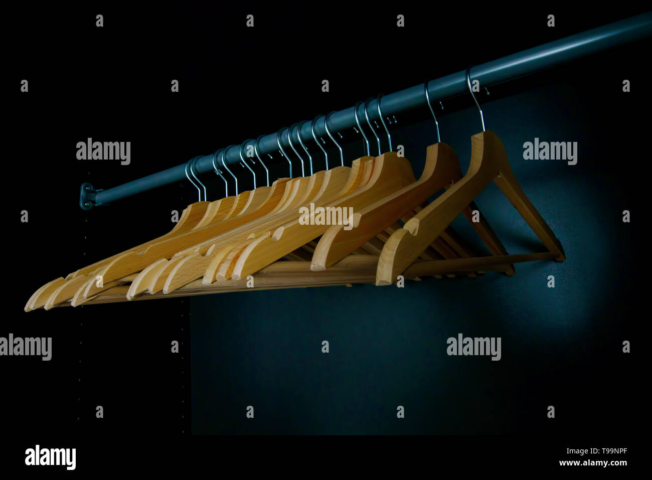 Empty wooden clothes hangers on a wardrobe rail, concept for expensive seasonal clothing desire and 'nothing to wear' or label-obsessed consumers Stock Photo