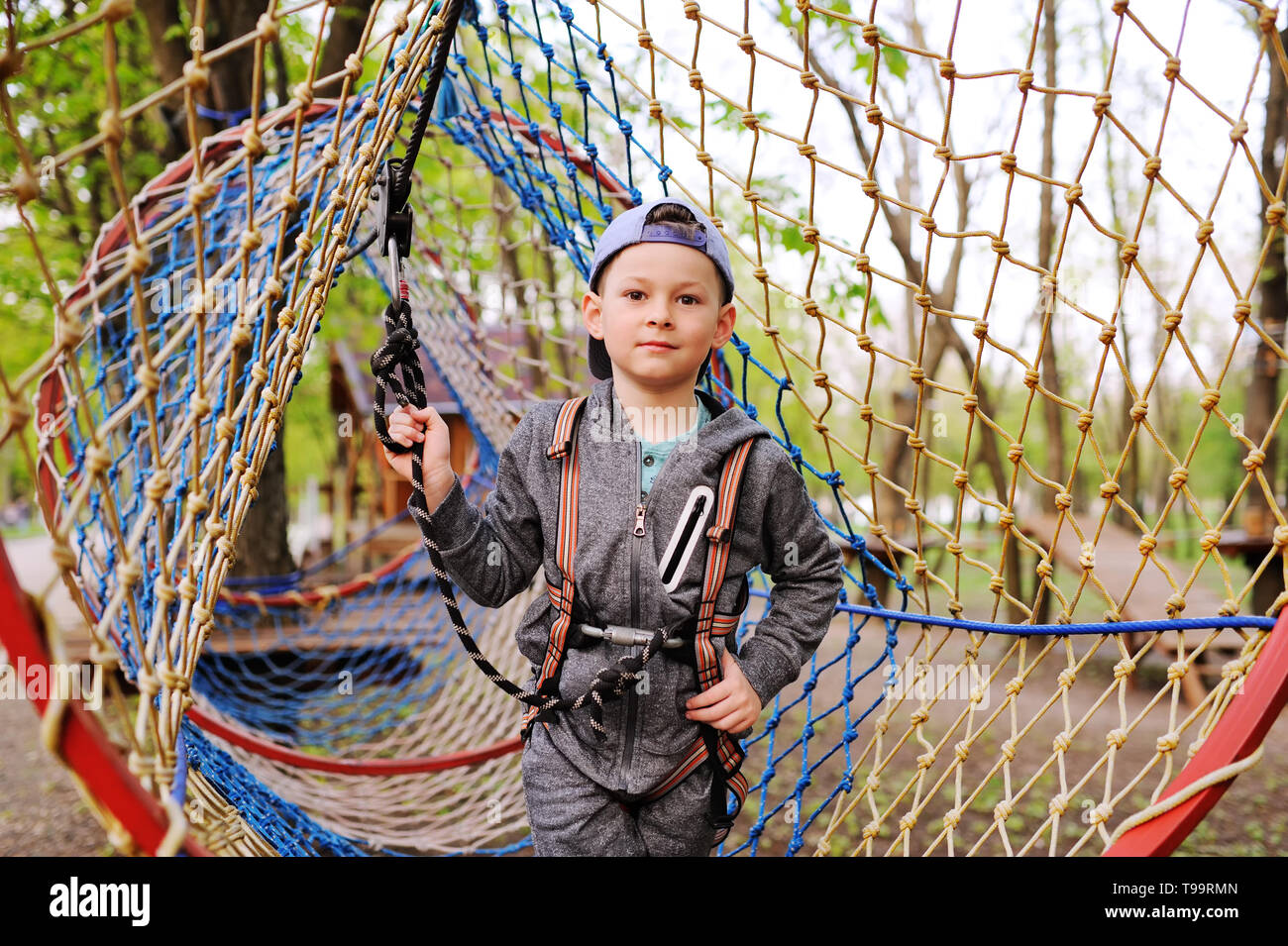 child preschooler boy is an obstacle in a safety alpinism equipment high rope course Stock Photo
