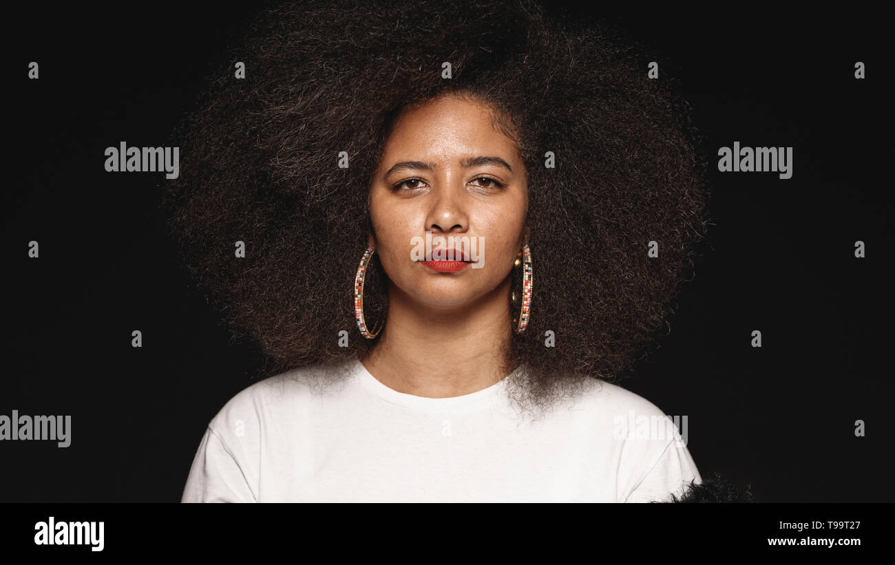 Woman in afro hairstyle isolated on black background. Close up of woman looking at camera. Stock Photo