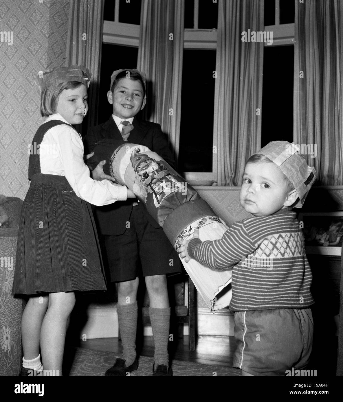 Children playing with a giant Christmas Cracker c1955  Photo by Tony Henshaw Stock Photo